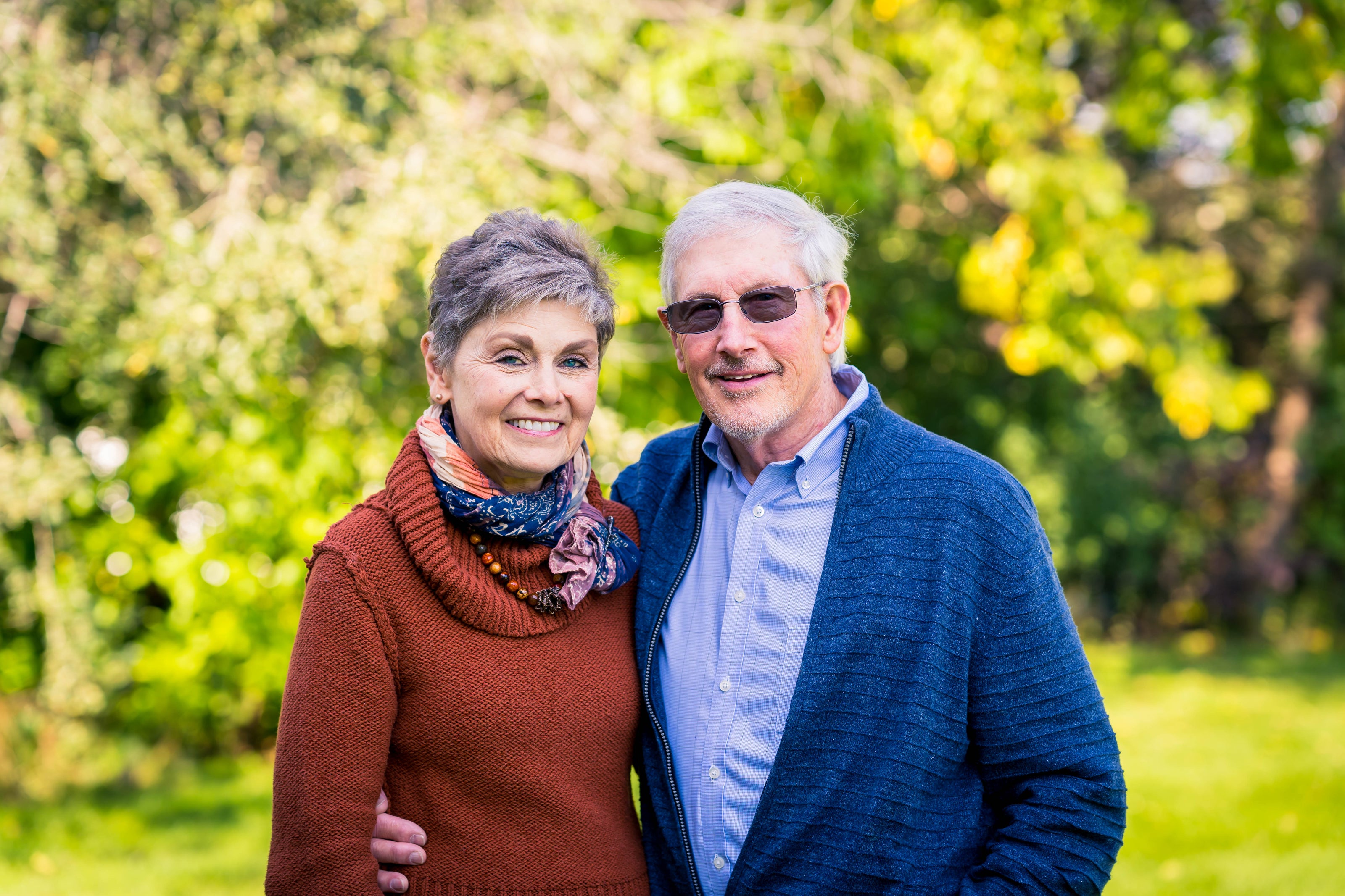 older couple portrait outside green trees