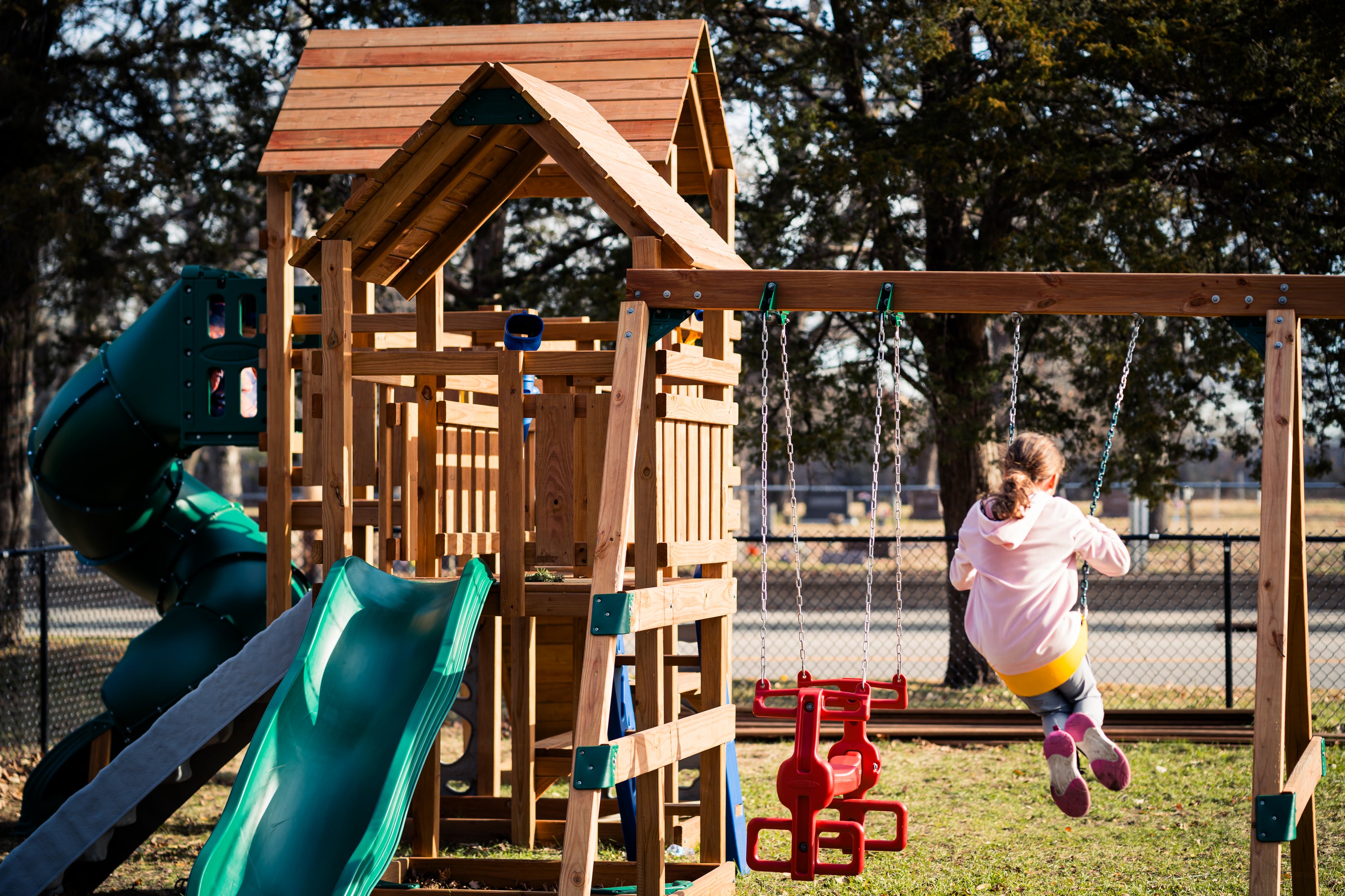 wooden playground with girl swinging